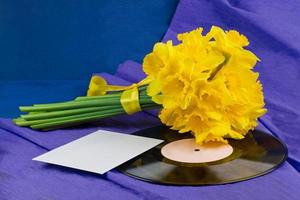 Narcissus flowers, envelope on background with vinyl record photo