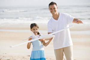 Hispanic girl and dad playing with toy on beach