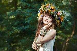 Beautiful girl with wreath on the head of  field flowers.