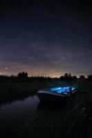 Barco azul y blanco iluminado sobre el río. foto