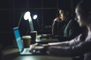 Asian businesswoman and businessman working hard late together  photo