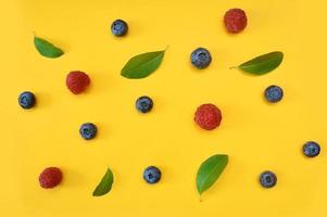 Summer blueberries and raspberries on yellow background photo