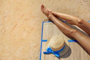 Female feet and a straw hat on the beach photo