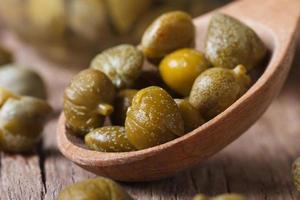 ripe capers in a wooden spoon macro horizontal