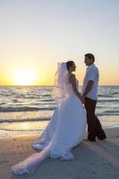 novios pareja casada puesta de sol playa boda foto
