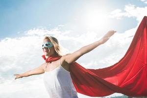 Blonde superhero standing over blue sky and arms outstreched photo