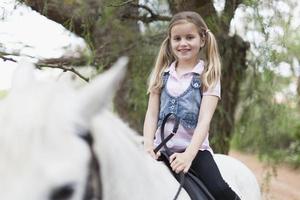 Smiling girl riding horse in park