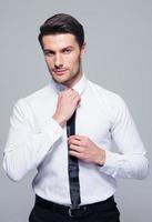 Handsome businessman straightening his tie