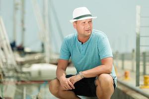 Fashion portrait of handsome man on pier against yachts