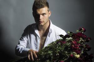 Retrato de hombre guapo con flores en estudio foto