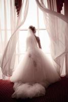 bride standing beside a large window