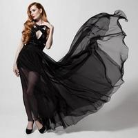 Fashion woman in fluttering black dress. White background.