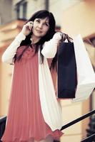 Fashion woman with shopping bags calling on mobile phone photo