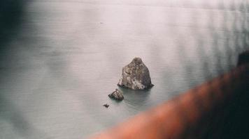 Rock formation on water through fence photo