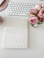 White covered book, keyboard and flowers photo