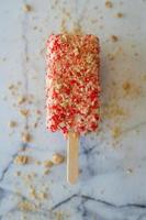 Pink ice cream on stick with toppings photo