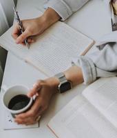 Man writing while holding mug photo