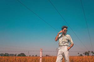 Man in sunglasses next to fence and field photo