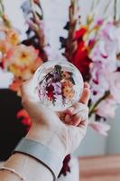 Person holding lensball in front of flowers
