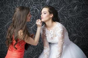 Makeup artist applies lipstick bride photo