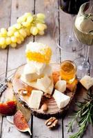 Cheese plate with honey, grape, wine in glasses photo