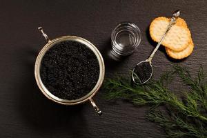 caviar negro servido sobre galletas saladas con vodka y aditivos foto