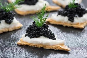 galletas saladas con queso crema y caviar negro foto