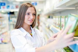 portrait of beautiful blonde female pharmacist reading a label photo