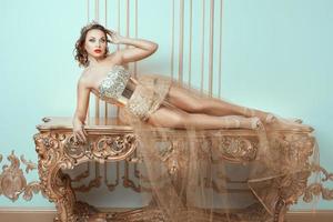 Fashionable woman lies on an expensive antique table. photo