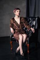 Bella mujer con vestido corto sentado en un sillón