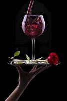 copa de vino tinto y rosa sobre negro