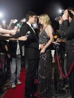 Couple Embracing On Red Carpet Surrounded By Paparazzi photo