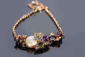 golden bracelet with precious stones on grey background