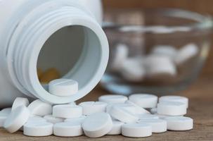 Pills in Medicine bottles on wood background photo