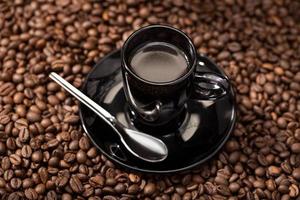 café expreso en taza negra y granos tostados foto