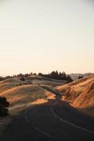 Winding road on brown grassy hills photo