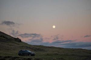 Car parked on grassy field at sunset photo