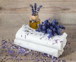 Lavender oil, lavender flowers and bath white towels . photo