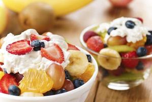 Sweet tasty fruit salad in the bowl with whipped cream