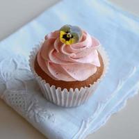 Homemade pink frosting vanilla cupcakes with edible flowers photo