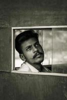 Young man looking through window photo