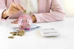 Businesswoman putting coins in piggy bank photo