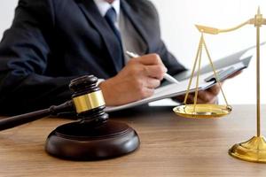 Lawyer taking notes with gavel and scales of justice on desk photo