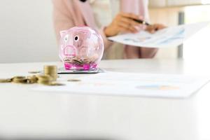 Businesswoman reviewing documents with piggy bank photo
