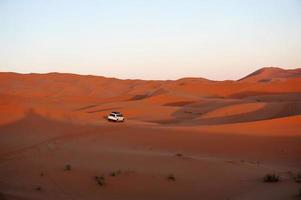 White vehicle driving through sand dunes photo