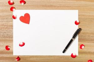 Top view of paper with a pen and red petals photo