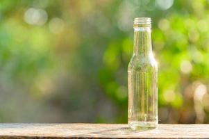 An empty glass bottle placed on a wooden table photo