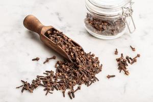 Cloves in a wooden scoop on a marble background photo