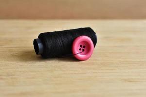 botón rosa e hilo de coser negro foto