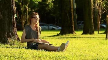mulher trabalhando em um laptop enquanto está sentada em um gramado verde durante o pôr do sol